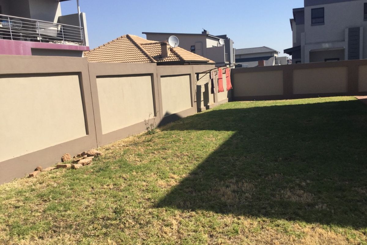 A private rear garden featuring a lawn area enclosed by high perimeter walls, providing a secure outdoor space.