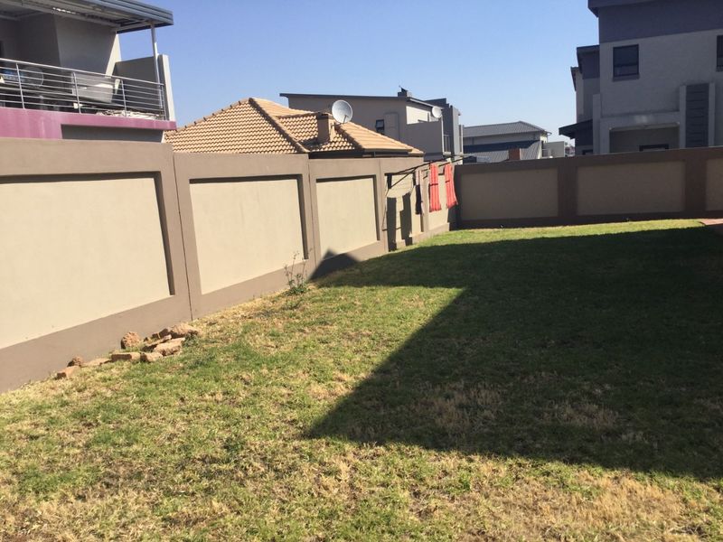 A private rear garden featuring a lawn area enclosed by high perimeter walls, providing a secure outdoor space.