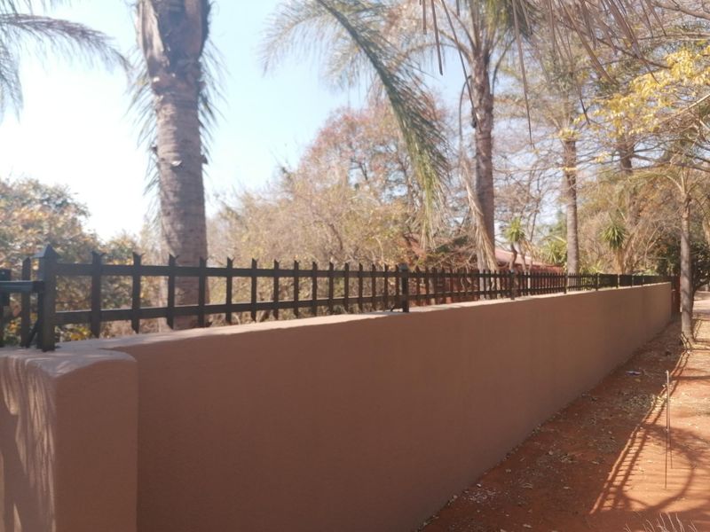 A well-maintained perimeter wall featuring secure metal fencing, providing clear boundary definition for the residential property.