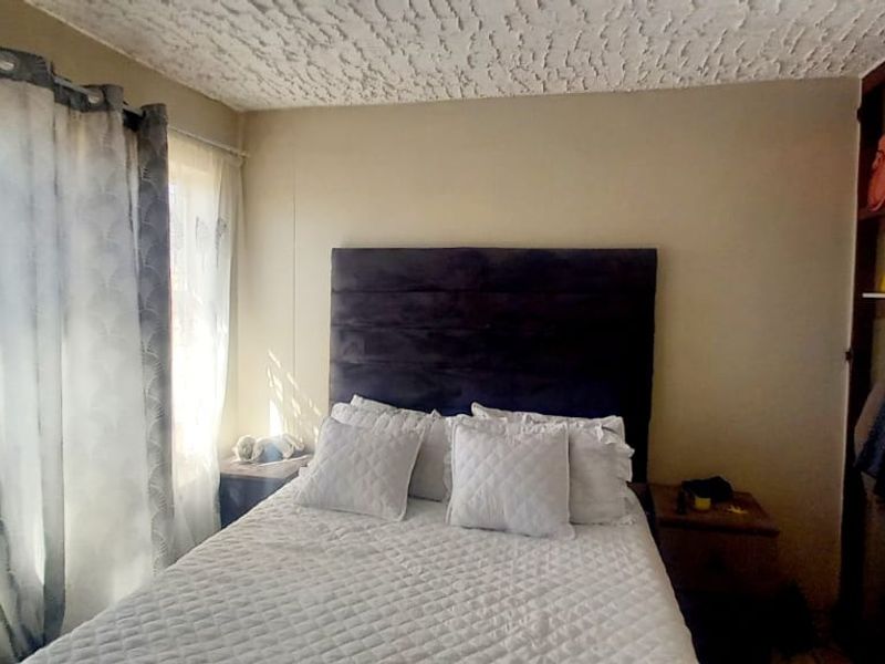 A bedroom featuring a built-in wardrobe and a textured ceiling, providing a functional living space.