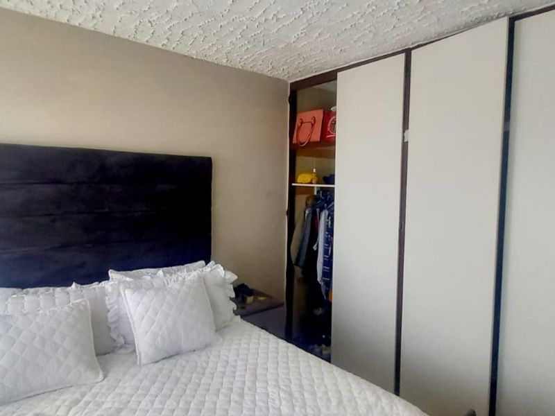 A bedroom featuring a built-in wardrobe with sliding doors and a textured ceiling finish.