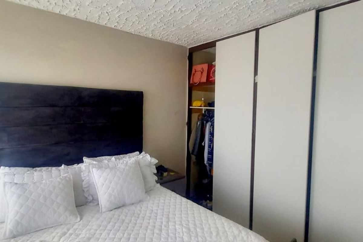 A bedroom featuring a built-in wardrobe with sliding doors and a textured ceiling finish.