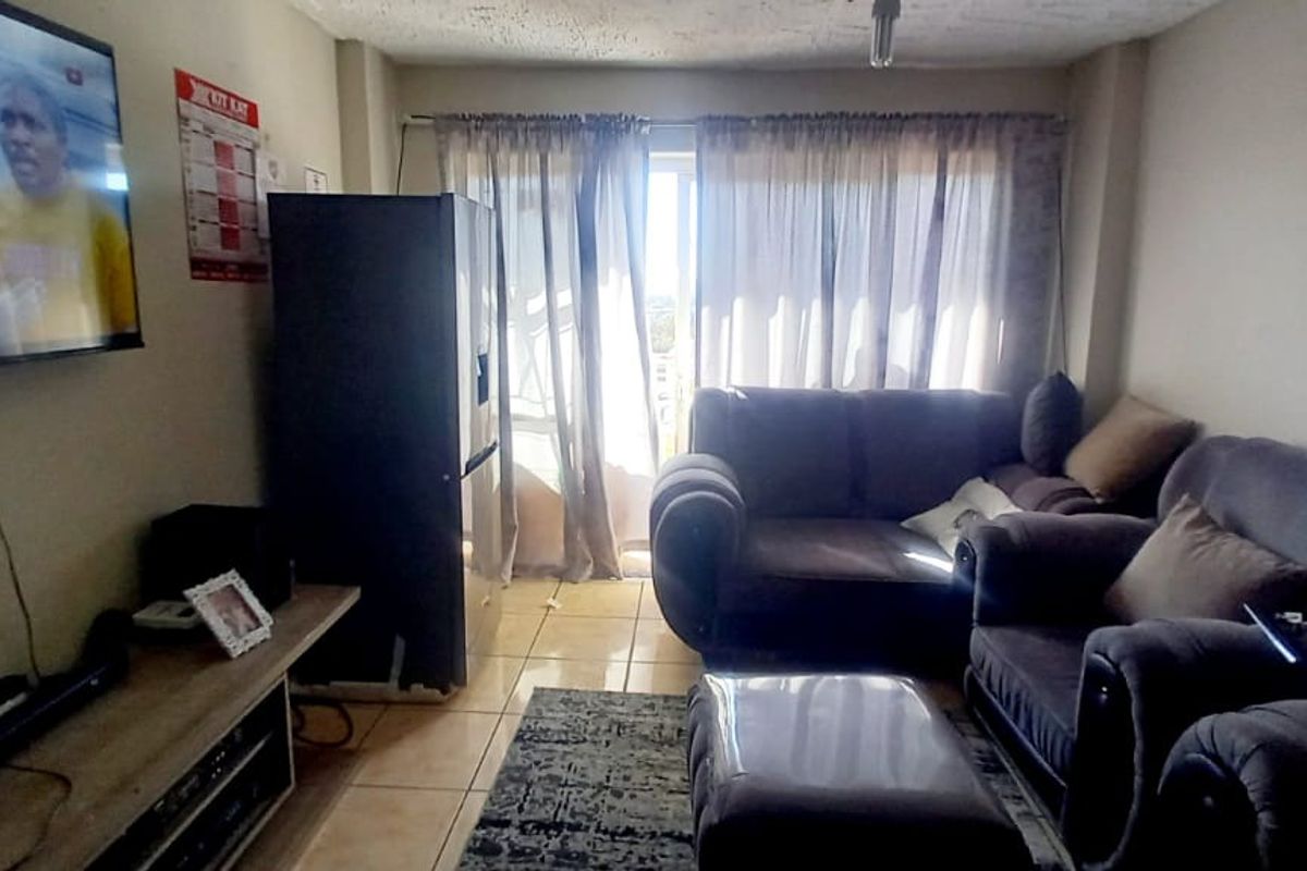 A living room area featuring tiled flooring and a sliding glass door leading to an outdoor space, with visible ceiling wear.