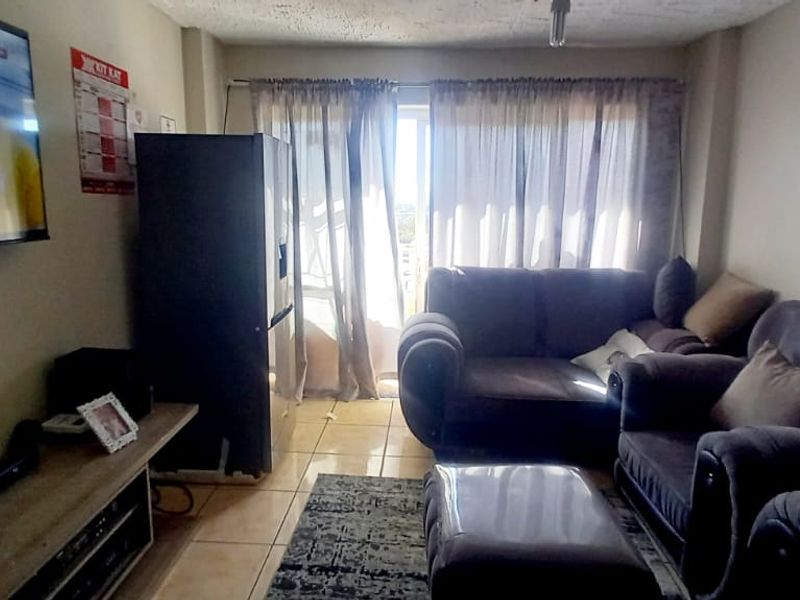 A living room area featuring tiled flooring and a sliding glass door leading to an outdoor space, with visible ceiling wear.