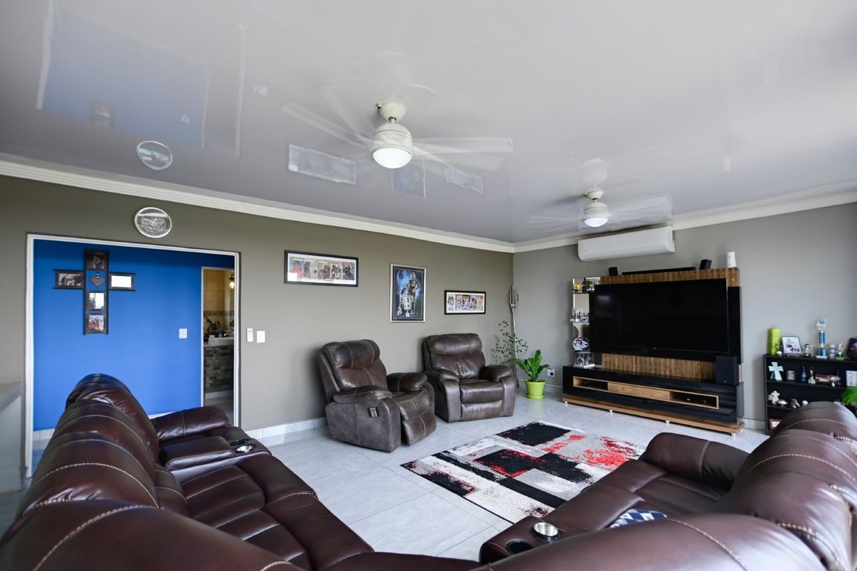 Spacious living room featuring a high-gloss ceiling, dual ceiling fans, and a wall-mounted air conditioning unit, providing a comfortable and modern living environment.