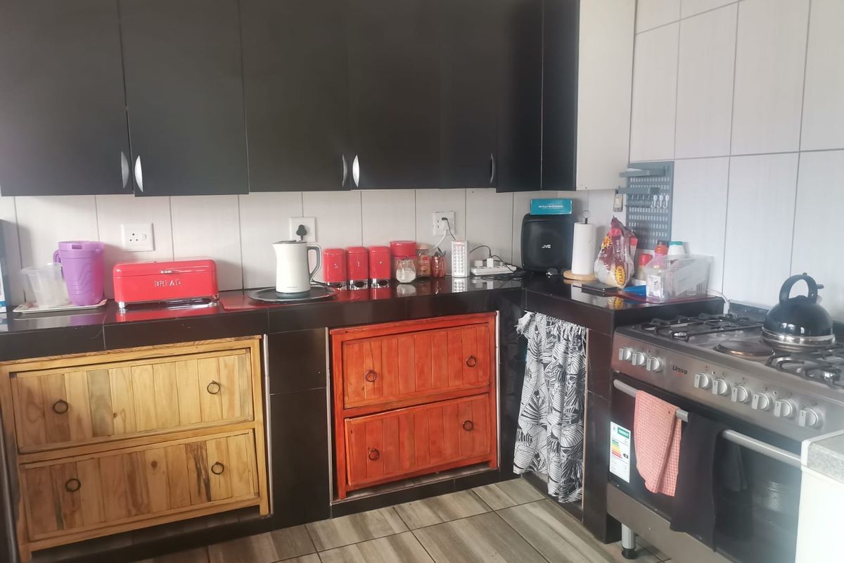A functional kitchen featuring dark upper cabinetry, tiled splashbacks, and a freestanding gas stove with oven.