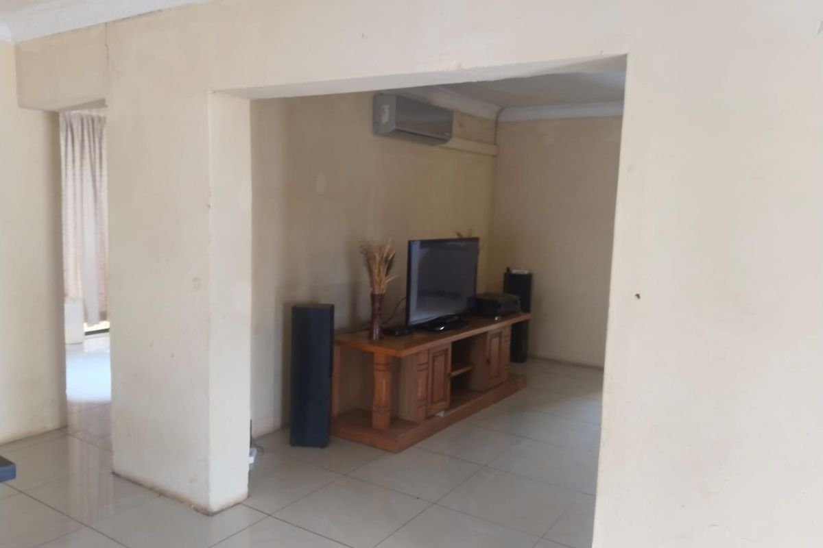 A living area featuring tiled flooring and a wall-mounted air conditioning unit, showing signs of wear on the walls.