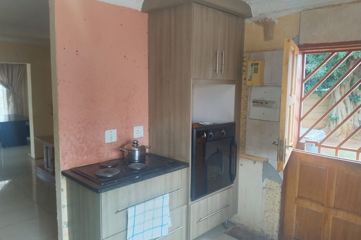 A kitchen area featuring built-in cabinetry, a hob, and an oven, currently requiring wall repairs and finishing to complete the space.