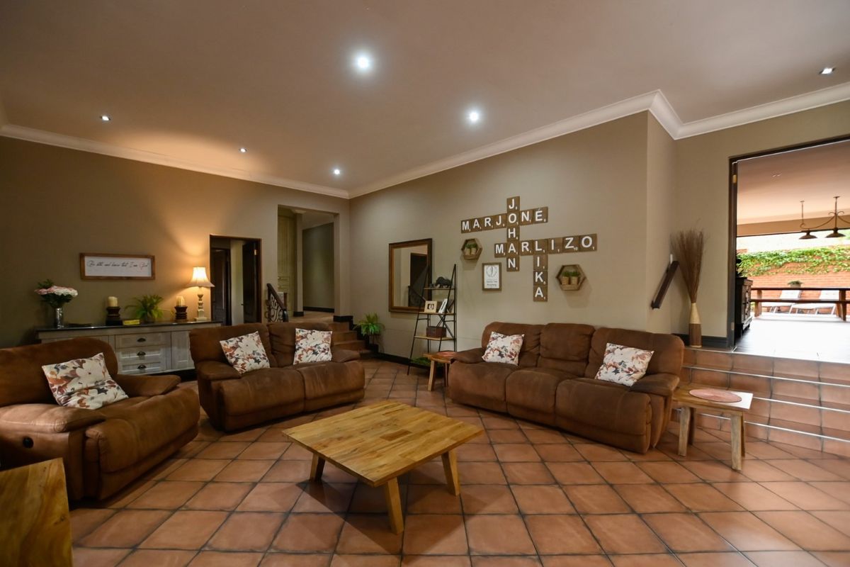 Spacious living room featuring terracotta floor tiles, recessed downlighting, and direct access to an outdoor patio area.