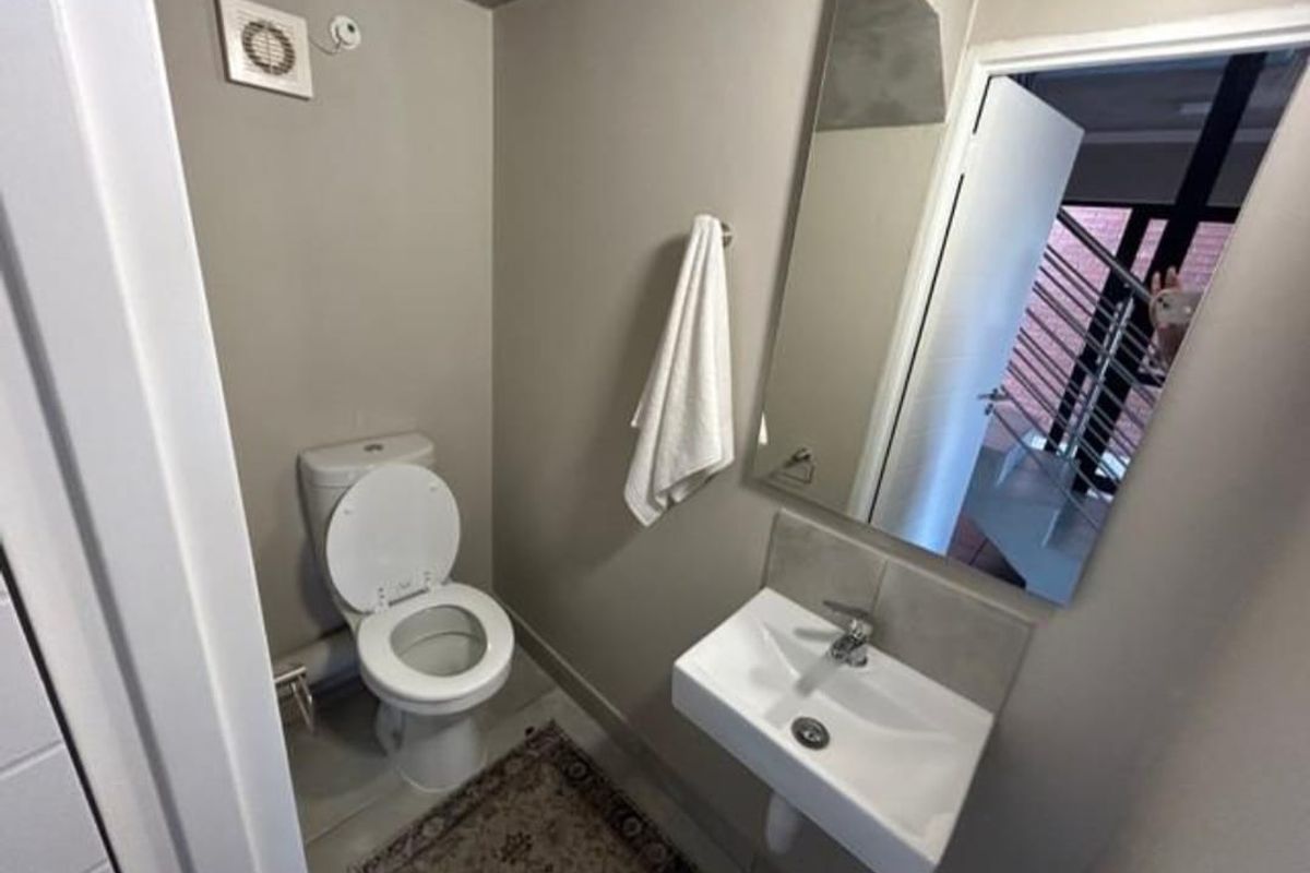 A compact guest bathroom featuring a wall-mounted basin, a modern toilet, and an extractor fan.
