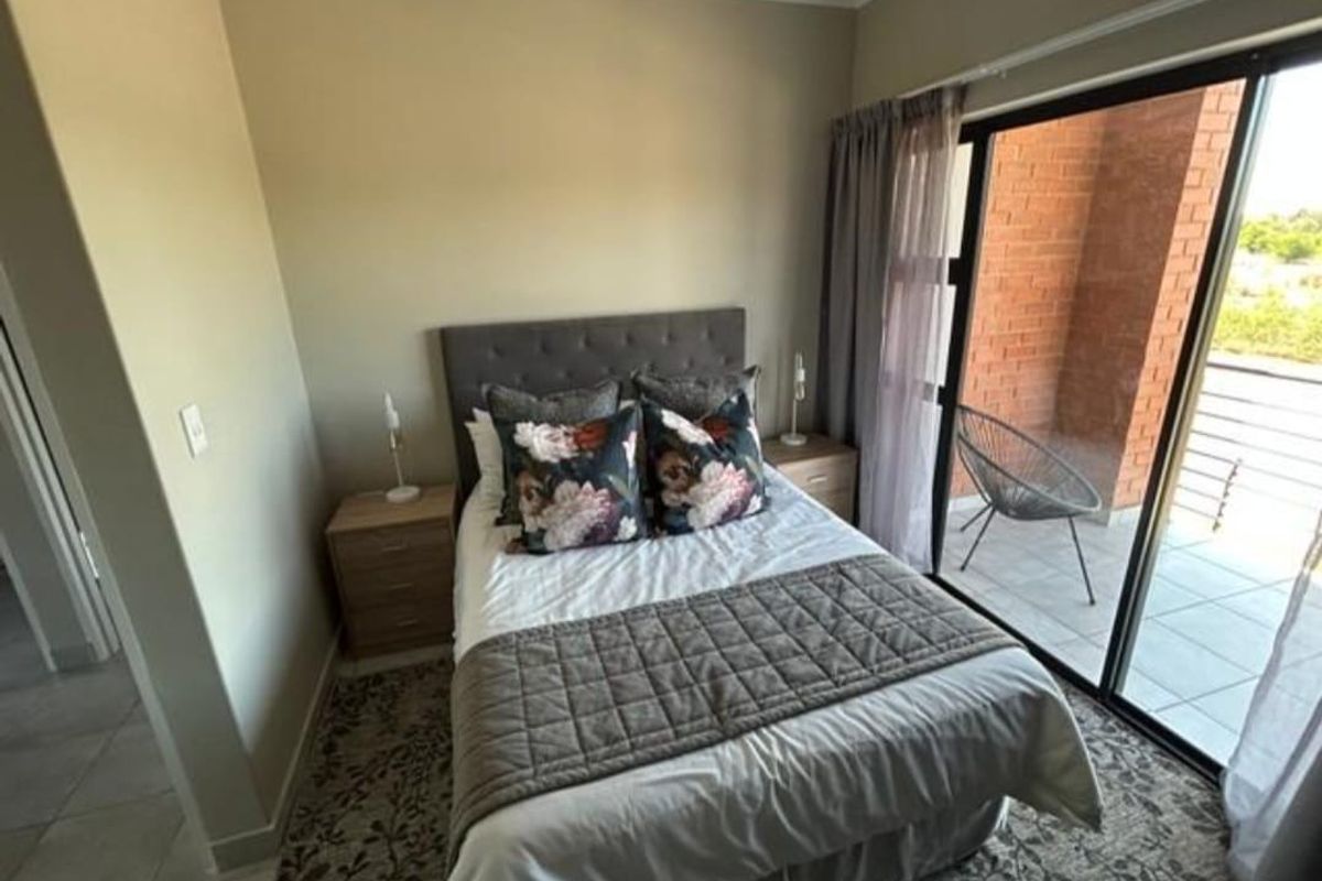 A well-lit bedroom featuring large sliding glass doors that open onto a private balcony, providing natural light and seamless indoor-outdoor flow.