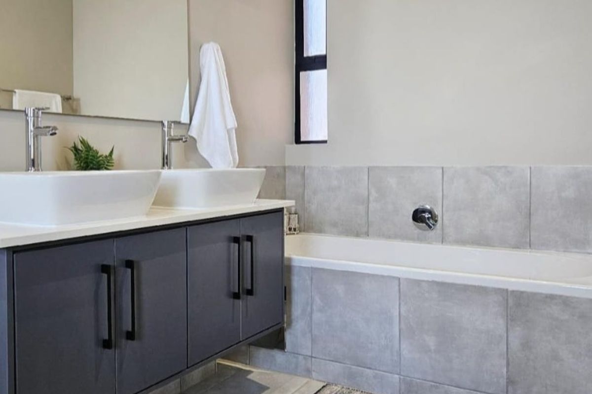 Modern bathroom featuring a floating double vanity with vessel sinks, a tiled bathtub surround, and contemporary fixtures.