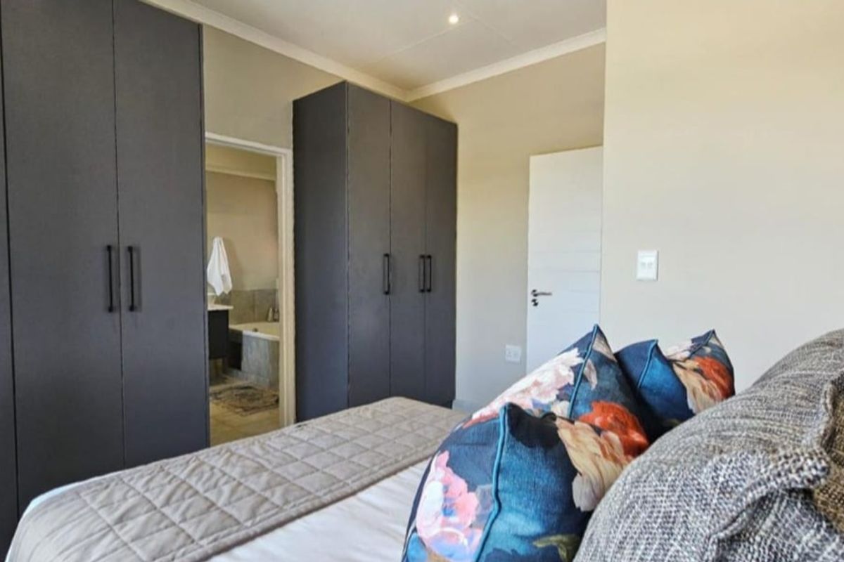 A well-lit bedroom featuring built-in dark grey cabinetry and direct access to an en-suite bathroom.