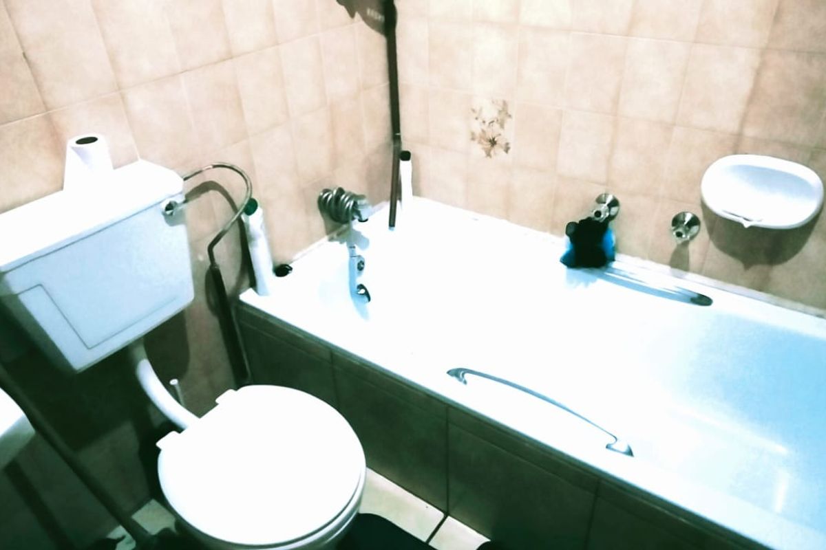 A functional bathroom featuring a standard bathtub, toilet, and tiled walls, offering a practical layout for daily use.