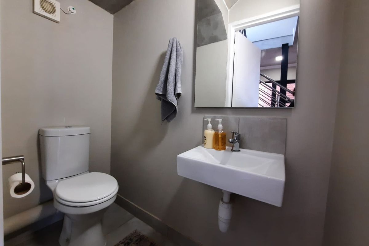 A compact guest bathroom featuring a wall-mounted basin, modern toilet, and extractor fan, finished with neutral wall tones.