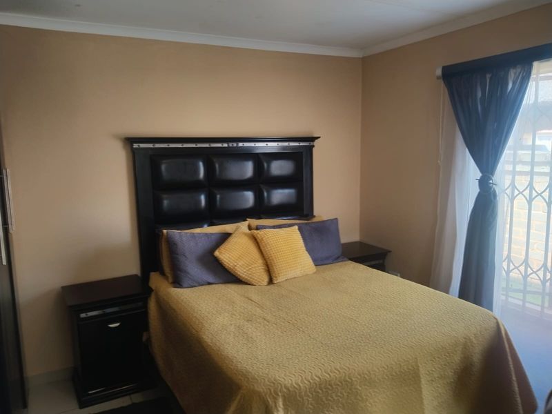 A bedroom featuring neutral wall tones, a sliding door with a security gate, and built-in storage space.