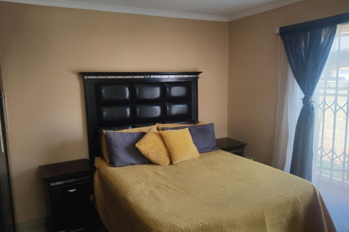 A bedroom featuring neutral wall tones, a sliding door with a security gate, and built-in storage space.
