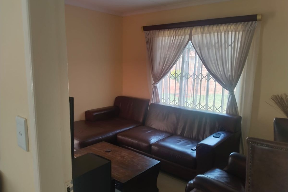 A cozy living room featuring tiled flooring and a window fitted with a security gate and curtain rod.