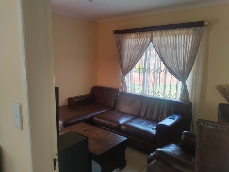 A cozy living room featuring tiled flooring and a window fitted with a security gate and curtain rod.