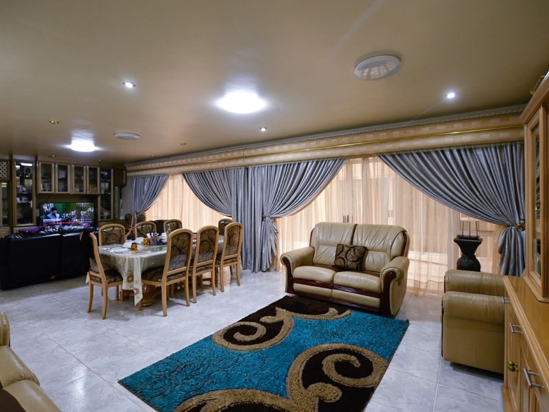 Spacious open-plan living and dining area featuring tiled flooring, recessed lighting, and large sliding glass doors with integrated drapery.