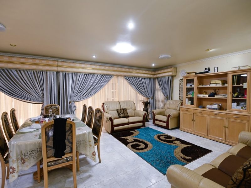 Spacious open-plan living and dining area featuring tiled flooring, recessed lighting, and built-in cabinetry, offering a functional layout for family living.