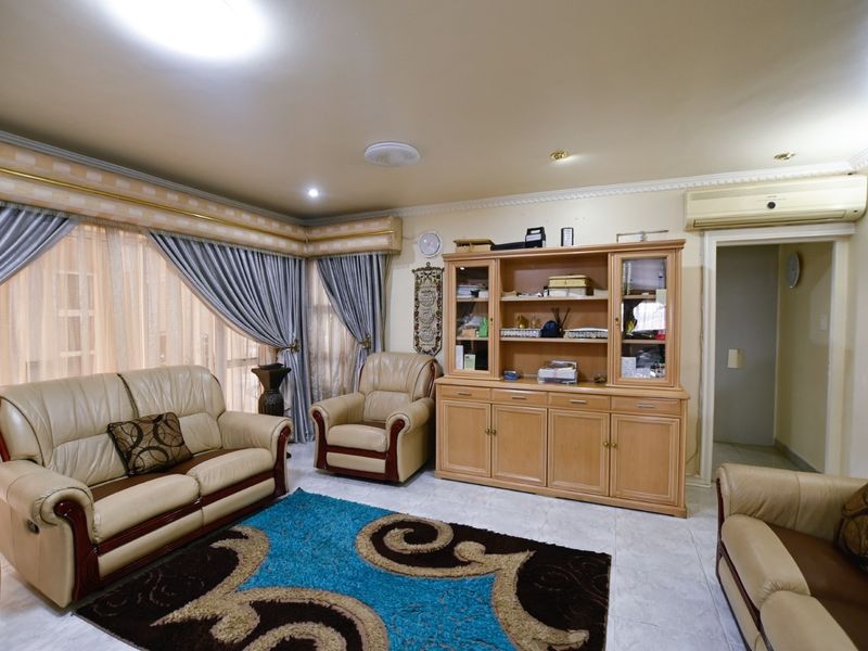 A comfortable living room featuring tiled flooring, recessed downlighting, and a wall-mounted split-system air conditioner, offering a functional and well-maintained space.