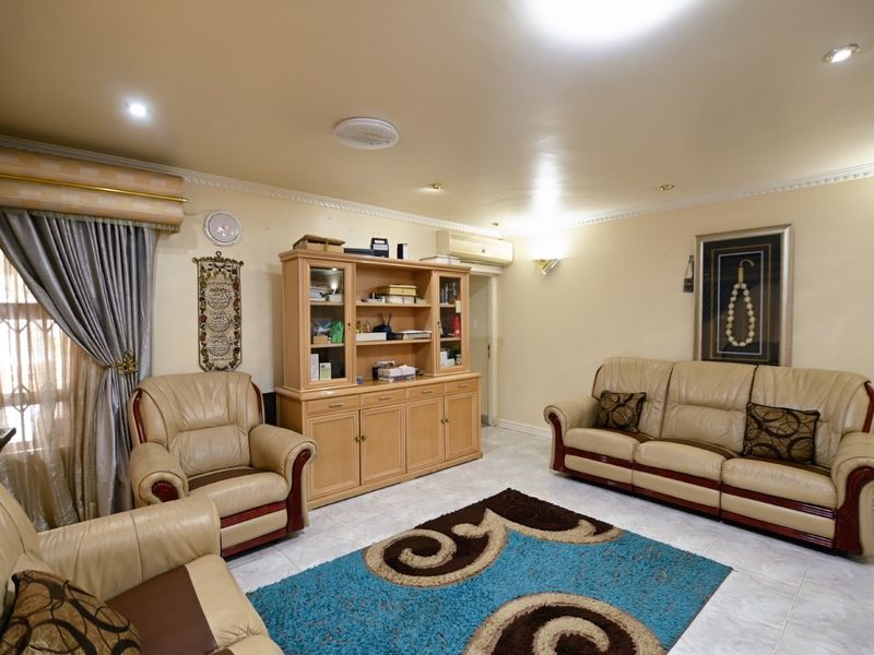 A comfortable living room featuring tiled flooring, recessed downlighting, decorative ceiling cornices, and a wall-mounted air conditioning unit.