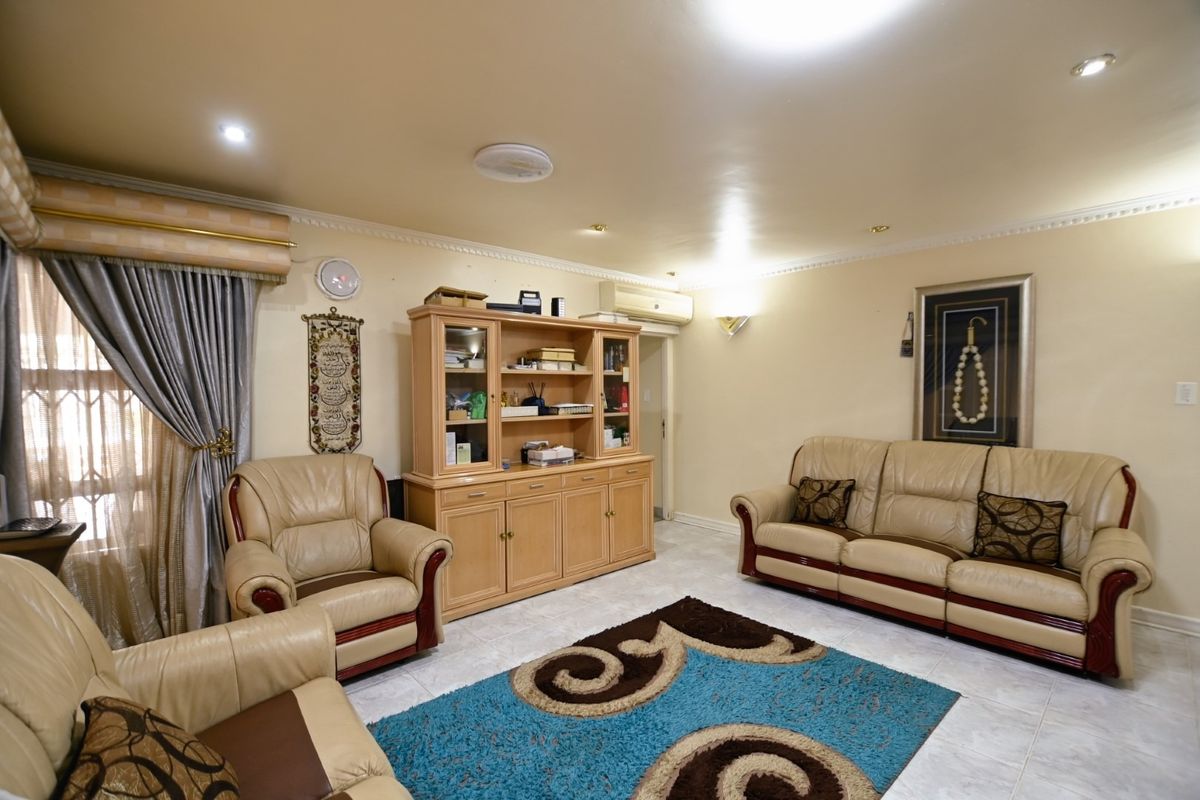A comfortable living room featuring tiled flooring, recessed downlighting, decorative ceiling cornices, and a wall-mounted air conditioning unit.