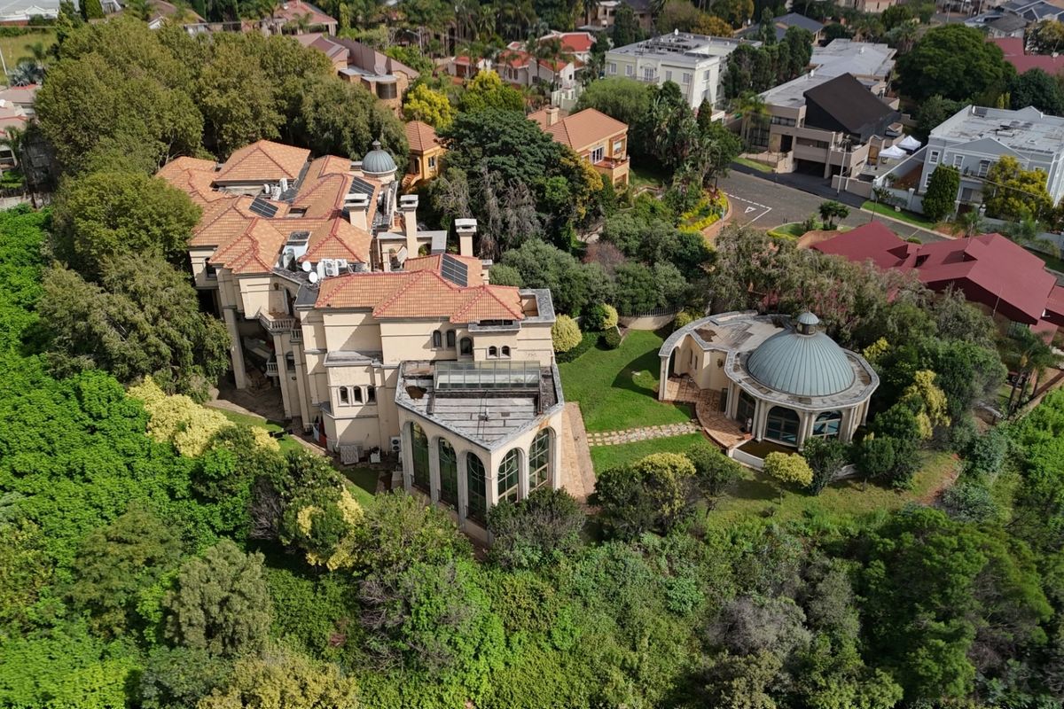 Aerial view of a large residential property featuring a multi-level main house with terracotta roofing and a separate domed structure set within landscaped grounds.
