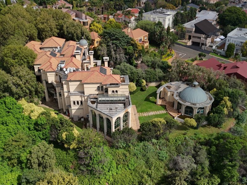 Aerial view of a large residential property featuring a multi-level main house with terracotta roofing and a separate domed structure set within landscaped grounds.