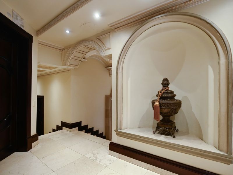 Elegant hallway featuring marble flooring, decorative ceiling molding, and a built-in arched wall niche with recessed lighting.