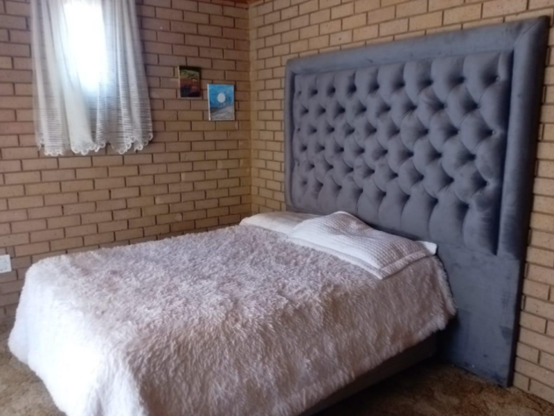 A bedroom featuring exposed brick walls and a timber ceiling, providing a rustic aesthetic.