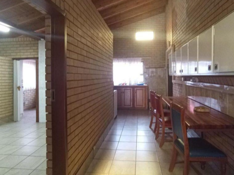 A kitchen area featuring exposed brick walls, timber beam ceilings, tiled flooring, and built-in cabinetry with a wooden counter.