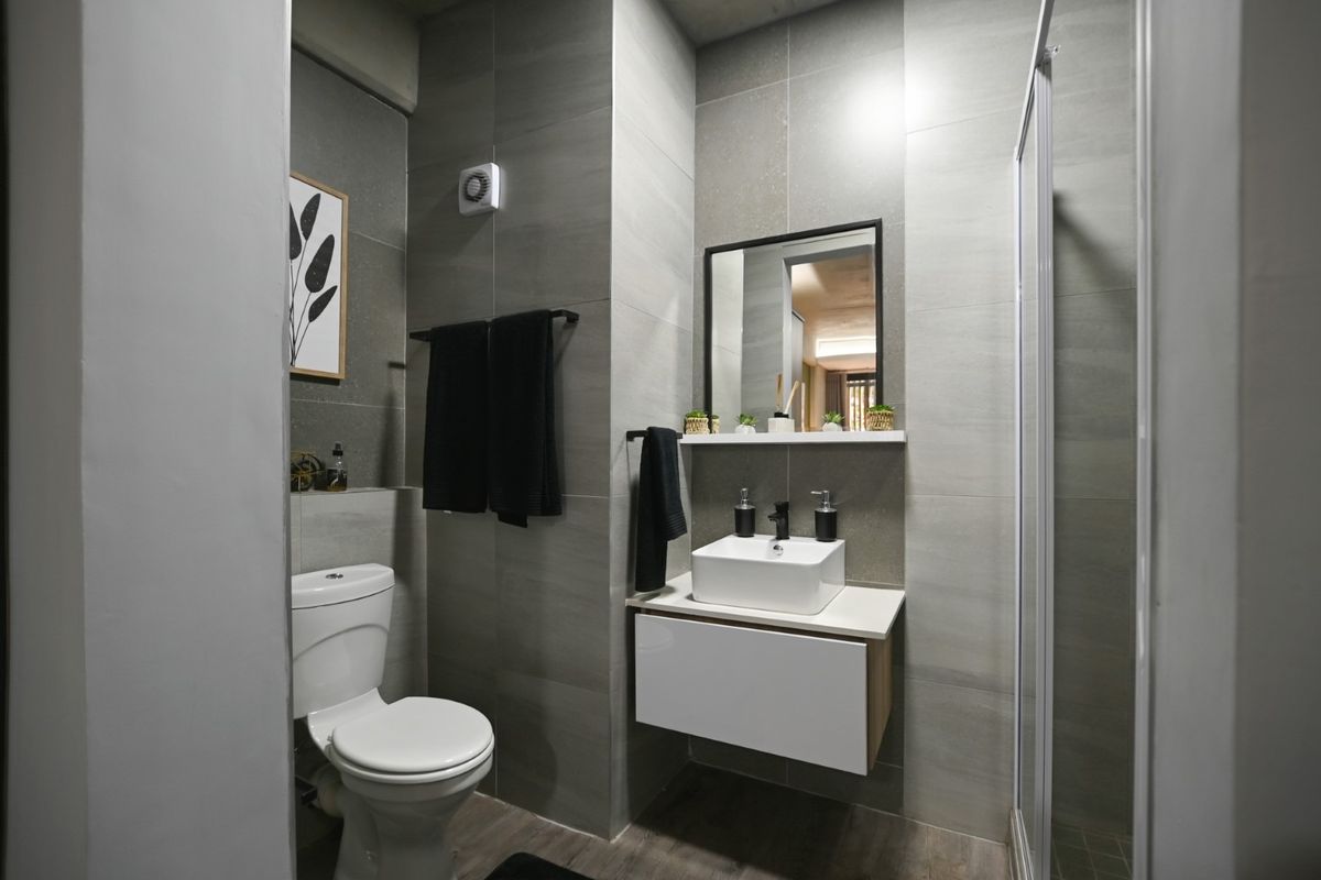 Modern bathroom featuring a wall-mounted vanity with vessel sink, glass shower enclosure, and neutral grey wall tiling.