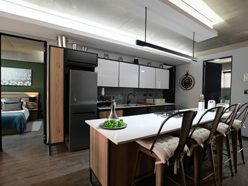Modern kitchen featuring a central island with a gas hob, sleek cabinetry, quartz countertops, and stylish pendant lighting under an exposed concrete ceiling.