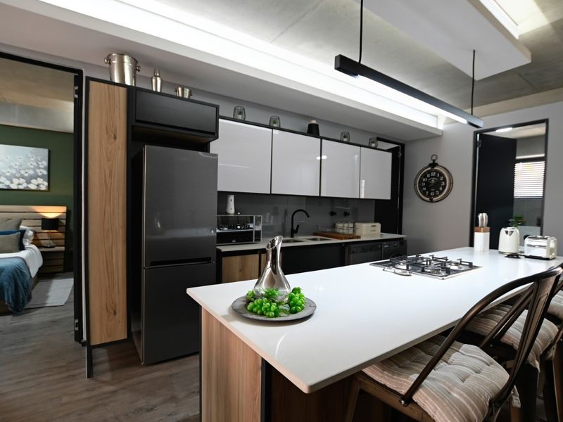 Modern open-plan kitchen featuring a central island with gas hob, sleek cabinetry, and high-end finishes, seamlessly integrated with the adjacent bedroom space.