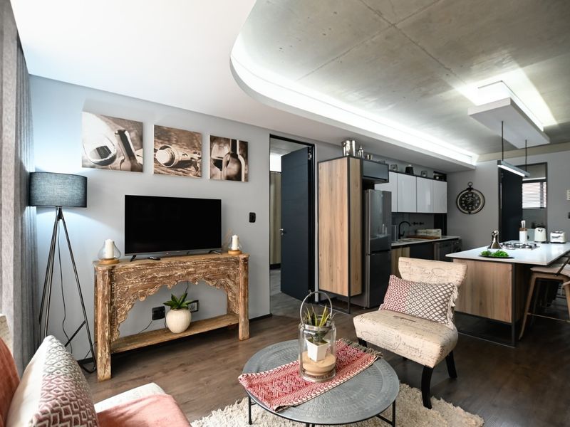Modern open-plan living area featuring an exposed concrete ceiling, sleek kitchen cabinetry, and a central island, creating a contemporary and functional living space.