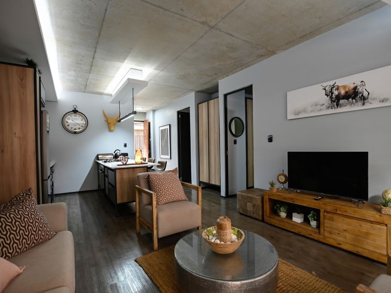 Modern open-plan living area featuring an exposed concrete ceiling, sleek kitchen island, and contemporary finishes throughout this well-maintained apartment space.