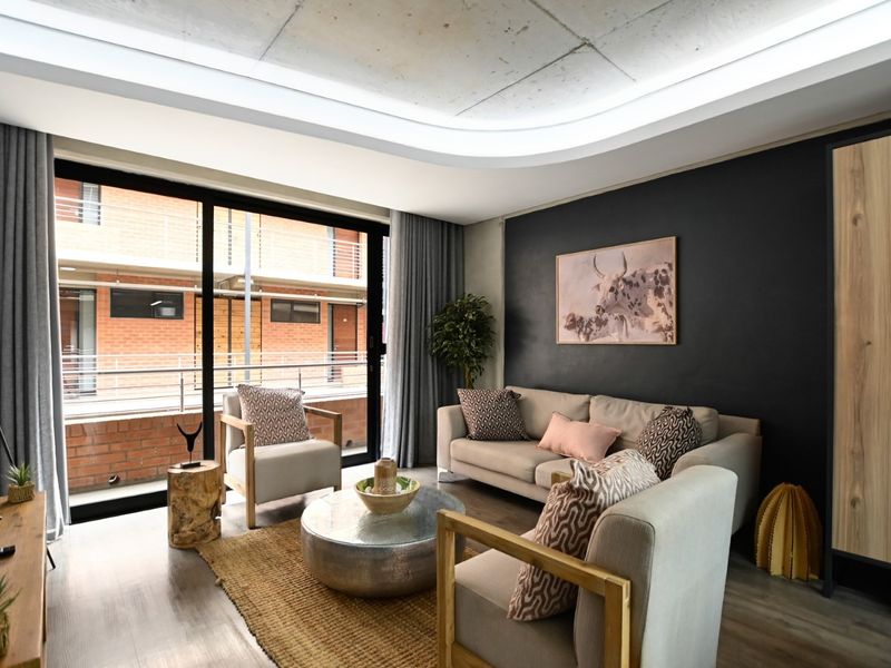 Modern living room featuring an exposed concrete ceiling with recessed lighting, laminate flooring, and large sliding glass doors leading to a balcony.