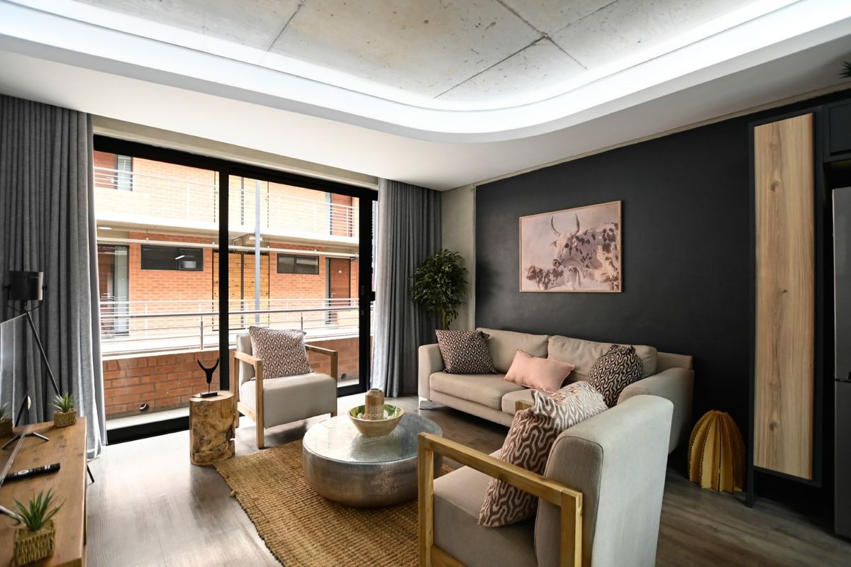 Modern living room featuring an exposed concrete ceiling with recessed lighting, laminate flooring, and large sliding glass doors leading to a balcony.