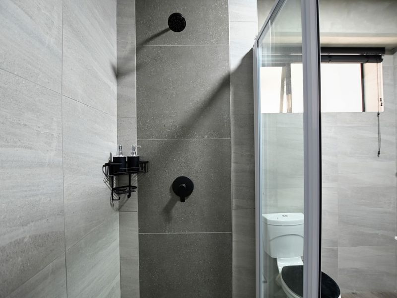 Modern bathroom featuring a glass-enclosed shower with matte black fixtures, neutral grey wall tiling, and a clean, contemporary aesthetic.