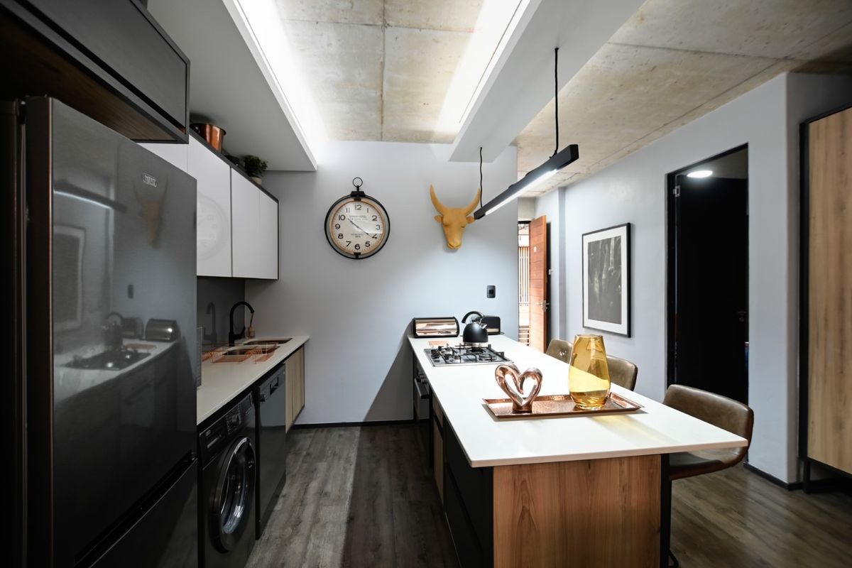 Modern kitchen featuring an island with integrated hob, sleek cabinetry, exposed concrete ceiling, and high-quality finishes in a contemporary open-plan layout.