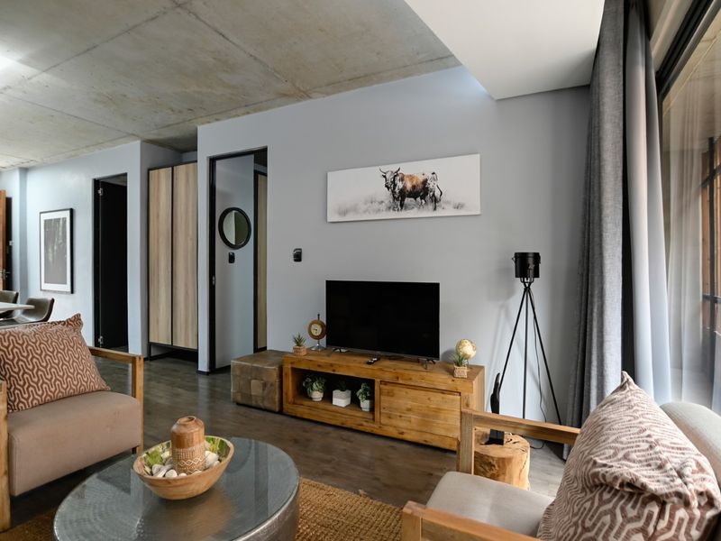 Modern living room featuring an exposed concrete ceiling, neutral walls, and large sliding glass doors leading to an outdoor area.