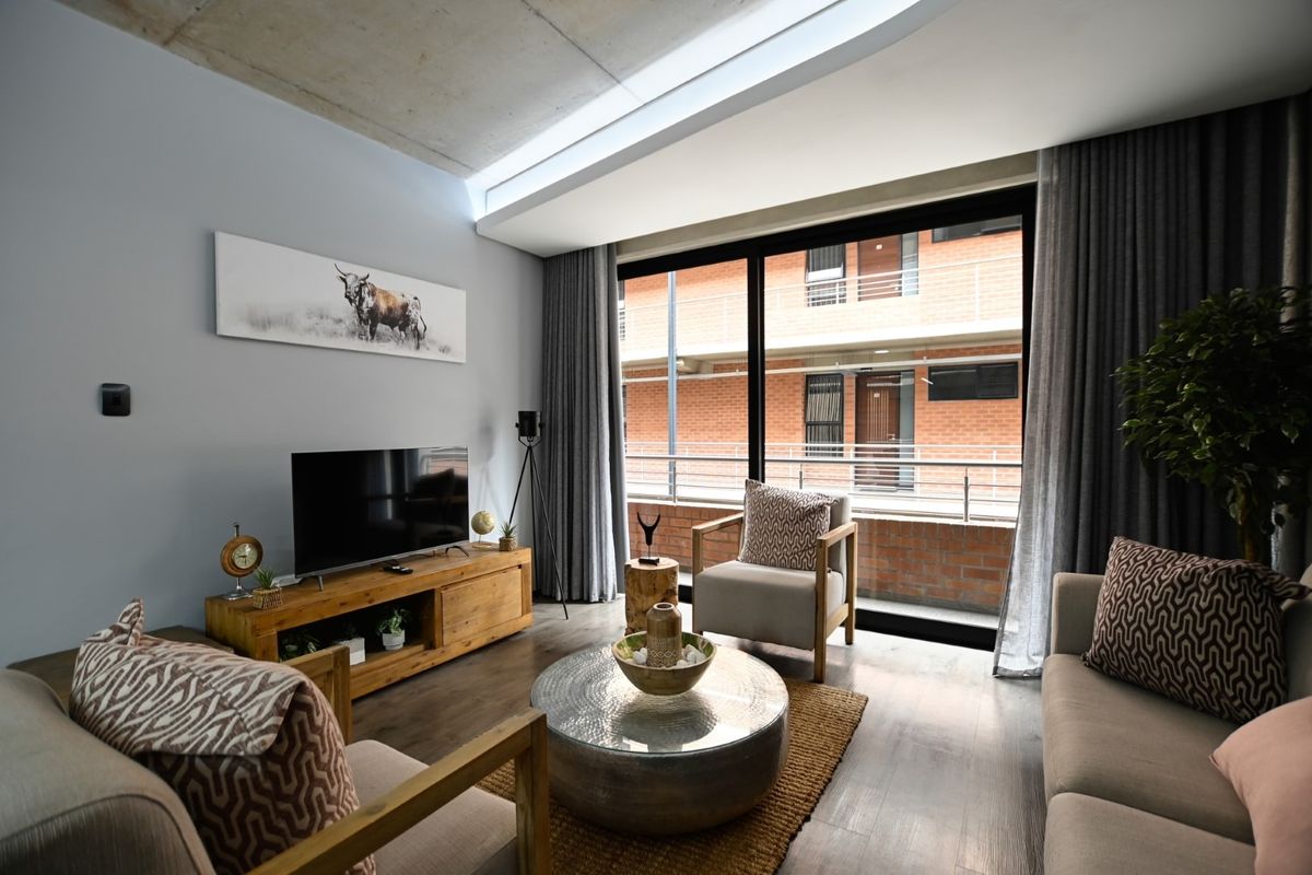 Modern living room featuring an exposed concrete ceiling, large sliding glass doors leading to a balcony, and high-quality laminate flooring.