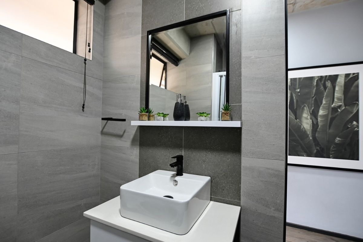 Modern bathroom featuring a contemporary vessel sink, black fixtures, a framed mirror, and sleek grey porcelain wall tiling.