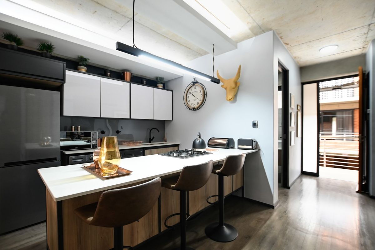 Modern kitchen featuring a central island with a gas hob, sleek cabinetry, and an exposed concrete ceiling, creating a contemporary and functional culinary space.