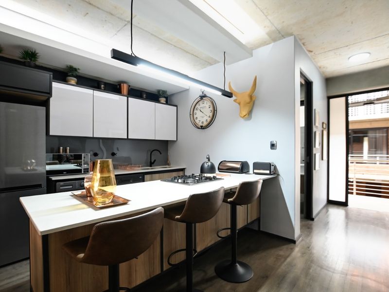 Modern kitchen featuring a central island with a gas hob, sleek cabinetry, and an exposed concrete ceiling, creating a contemporary and functional culinary space.