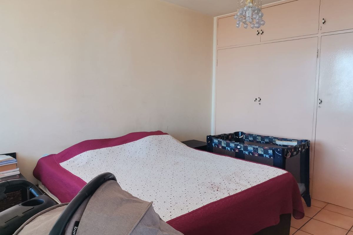 A bedroom featuring built-in cupboards and tiled flooring, offering a functional space with potential for modernization.