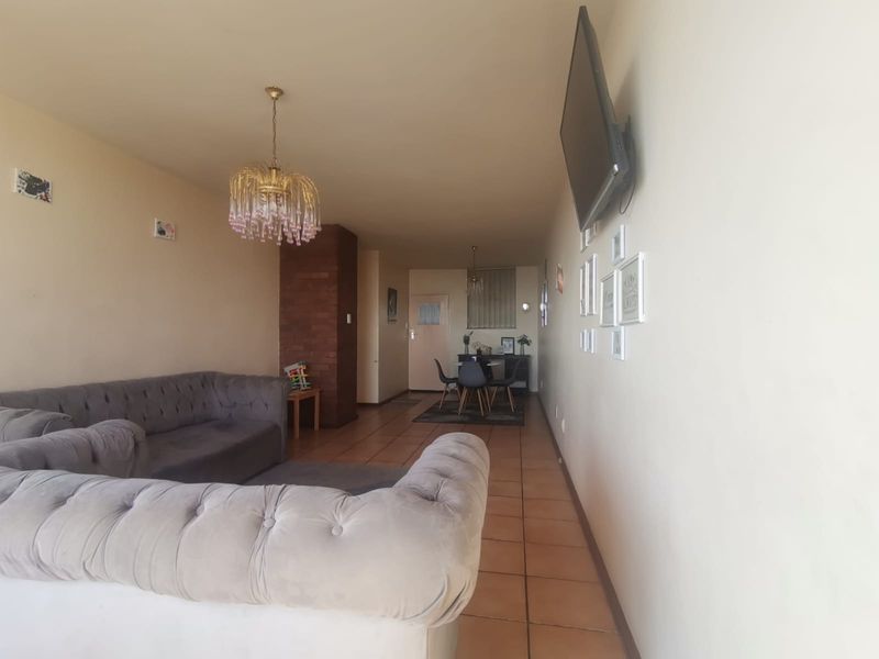 Open plan living and dining area featuring tiled flooring and a distinctive brick feature pillar, providing a functional layout for daily living.