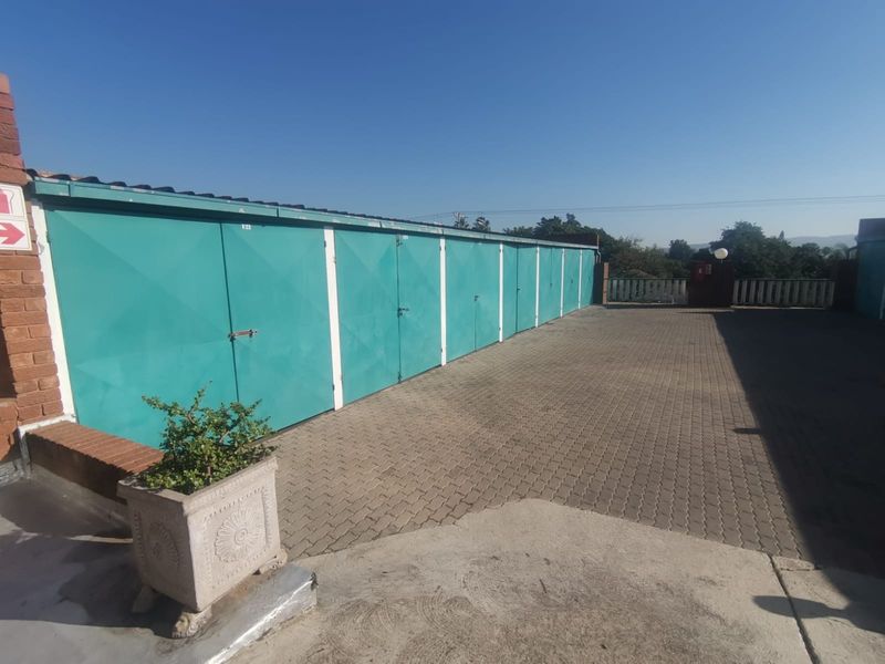 A row of secure metal garage units with a paved driveway area, providing functional parking space for the apartment complex.